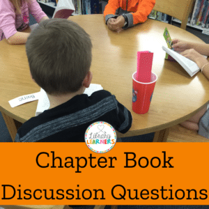 students at library table reading and discussing a chapter book.