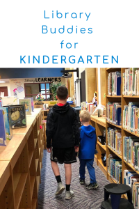 older student helping kindergarten student in school library